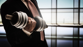 A man in a business suit lifting weights for muscle development.