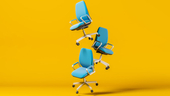 hree blue office chairs float in front of a yellow background.