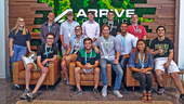 Arrive Logistics team photo with the company logo on the wall behind them