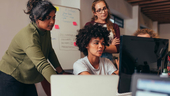 Software developers looking at a monitor discussing source code