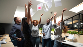 Diverse group of coworkers throwing papers in the air to celebrate