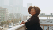 Portrait of Jackie Ivy-Hardin standing on a balcony overlooking a city street.