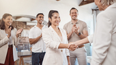 Three clapping coworkers and new hire handshake