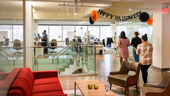 CarGurus office interior with employees milling about and a “Happy Halloween” banner hanging from the ceiling.