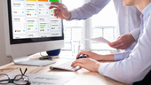 Manager points at computer screen as staff member types