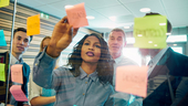 Group of colleagues brainstorming with post it notes on the wall