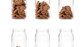 Six glass jars containing cookies but each jar progressively has less cookies until the sixth jar that is empty