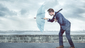 A tech employee staying resilient pushing against the wind in the rain.