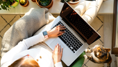 A remote worker with her cat next to her laptop
