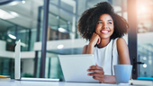 woman in an office using a laptop and digital tablet