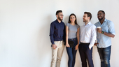 A group of four young businesspeople, talking and smiling.