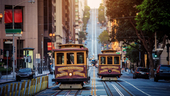 Two trolleys travel through the downtown San Francisco area.