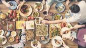 An aerial-view image of friends gathered around a table eating and drinking together.