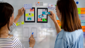 Two designes holding up user journey pictures.