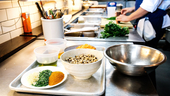 professional kitchen with ingredients prepped and cook chopping in the background