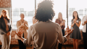 A leader faces four clapping team members.