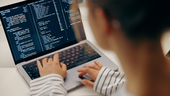 Close-up photo of female software engineer writing code on laptop.