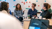 Ontra coworkers having a team meeting in the office with post it notes on the wall in the background
