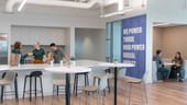 Employees in Bonterra's office. On the right there are two employees at a table. On the left there are three in the kitchen. Between is a wa