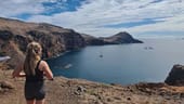 Partner Delivery Consultant Kaitlin Fox with her back to the camera, standing on a cliff overlooking water.