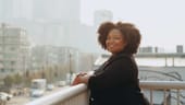 Portrait of Jackie Ivy-Hardin standing on a balcony overlooking a city street.