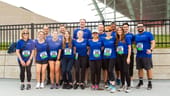 Members of the Wipfli team assemble for an outdoor racing event. They wear matching blue shirts and participation numbers.