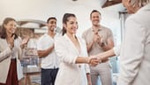 Three clapping coworkers and new hire handshake