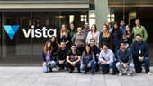 Group photo of Vista team members with company logo on the window behind them