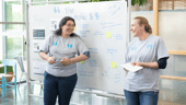 Two Redgate co-workers smile as they lead a presentation.