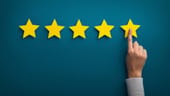 Concept photo of a five star rating with a hand selecting one star