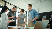 Team of four colleagues standing at table having discussion
