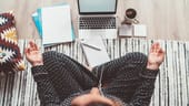 A woman meditates in front of her computer.