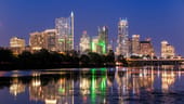 Downtown Austin, Texas at night with lights from skyscrapers reflecting on the near lake.