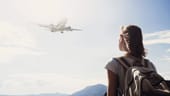 Photo of woman with backpack on looking to an airplane in the sky