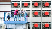 Some workers stand on a hydraulic lift in front of a data center..