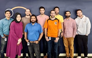 a team stands in front of a wall
