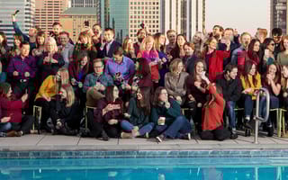 Large team sitting in front of a pool sharing content and taking photos on smartphones