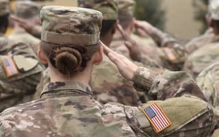 Image of a group of military service members in uniform, saluting ahead