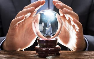 A pair of hands hover over a crystal ball.