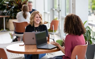 Workiva employees talking over their computers.
