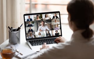 A woman attends a virtual team meeting at home.