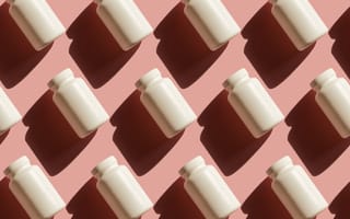 Stock photo of blank pill bottles against a pink background.
