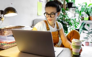 Young professional woman works from home with plants in background