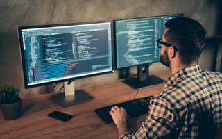 Image of a software developer working in front of two computer monitors.