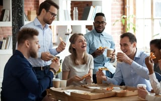 Employees gatherd around sharing a pizza