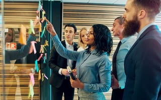 Creative group of business people brainstorming putting sticky notes on glass wall in office