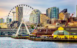 Seattle waterfront and skyline, with the Space Needle showing through the spokes of the Great Wheel ferris wheel in the foreground