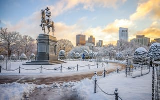 Boston Public Garden in winter with snow covering the ground near a statue of George Washington.