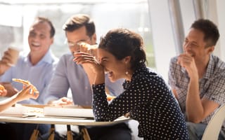 A group of employees laugh during a team lunch.