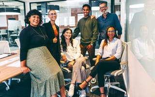 Group of happy businesspeople smiling at the camera in a boardroom.